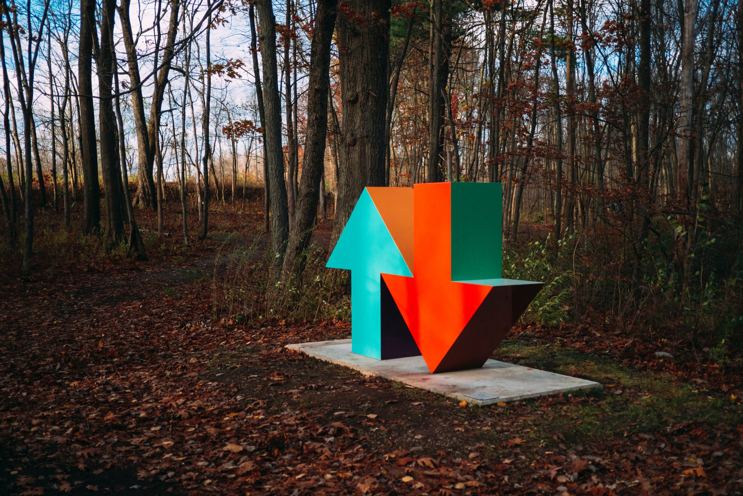 Neon blue and red arrow sculpture in the woods