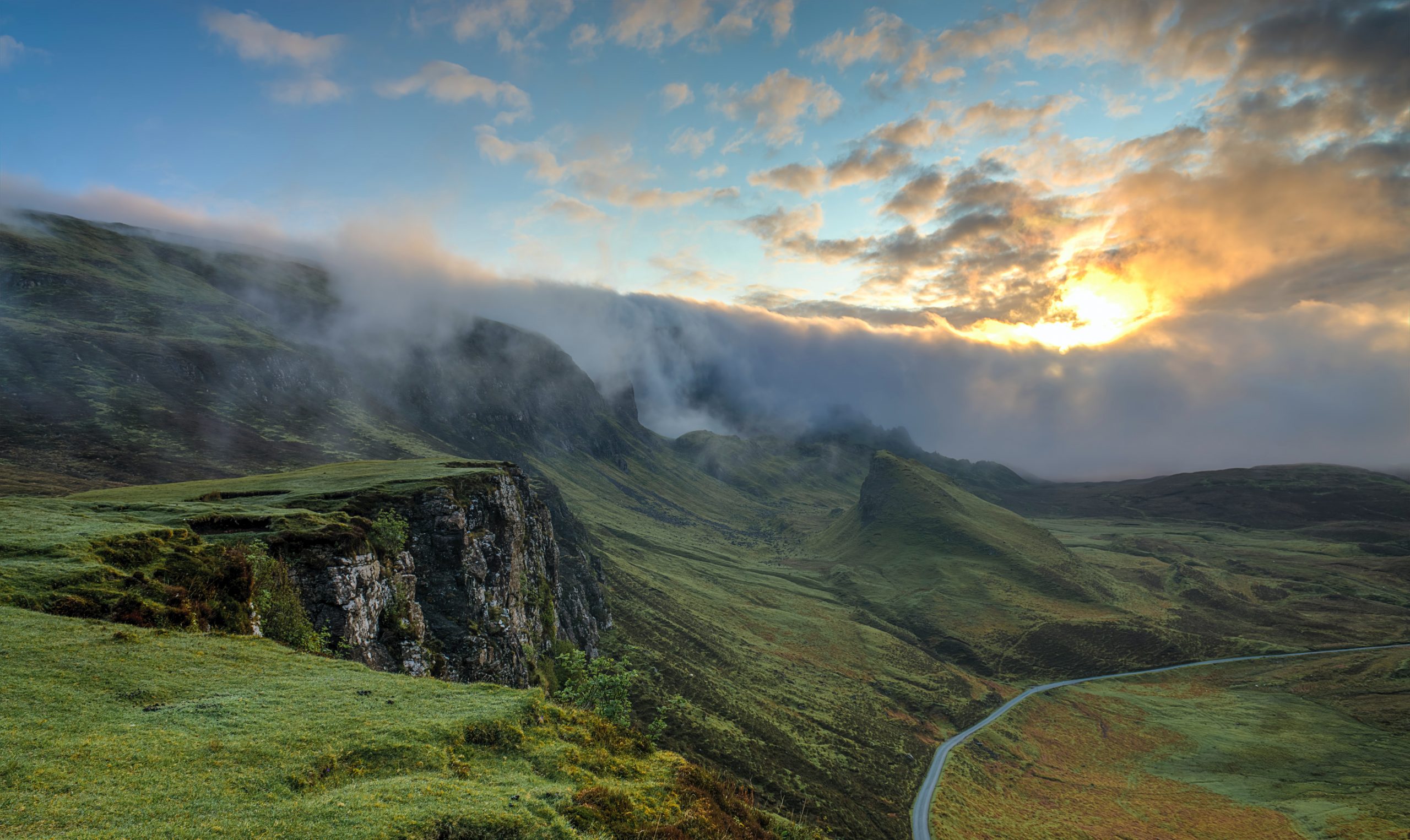 Misty clouds rolling over rocky mossy green mountain side